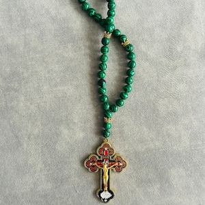 May include: Green malachite rosary beads with a gold-toned cross pendant. The cross features a detailed depiction of Jesus Christ.