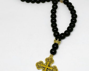 May include: Black beaded rosary with a gold cross pendant. The beads are round and the cross has a detailed design.