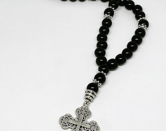 May include: Black beaded rosary with a silver cross pendant. The beads are black and the cross is silver with intricate details.