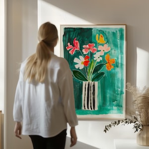 Könnte beinhalten: Ein gerahmtes Aquarellgemälde mit bunten Blumen in einer schwarz-weiß gestreiften Vase vor grünem Hintergrund. Das Kunstwerk zeigt rosa, rote, weiße und orangefarbene Blumen. Das Gemälde wird an einer weißen Wand ausgestellt.