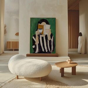 May include: An interior scene featuring a modern living room with a large abstract painting of a person reading a book and holding a cup. A white, organic-shaped ottoman and a small wooden table with a decorative object are in the foreground.