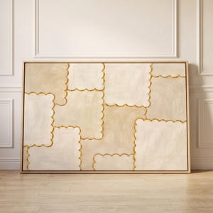 May include: A rectangular canvas painting in a light wood frame featuring an abstract pattern of overlapping square shapes with scalloped edges. The composition uses a palette of cream, beige, and tan tones with gold-colored outlines.