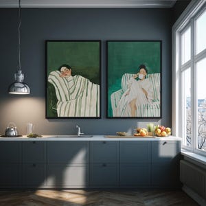 May include: Two framed art prints depicting figures in relaxed poses. One shows a person reclining, wrapped in a striped blanket, and the other shows a person seated, holding a cup. The artwork has a green and white color scheme.