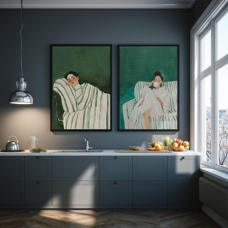 May include: Two framed art prints depicting figures in relaxed poses. One shows a person reclining, wrapped in a striped blanket, and the other shows a person seated, holding a cup. The artwork has a green and white color scheme.