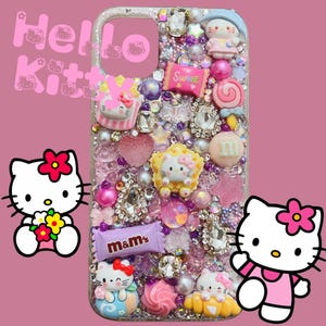 Pu&ograve; includere: Una custodia per telefono rosa Hello Kitty con strass, glitter e vari ciondoli, tra cui personaggi Hello Kitty, caramelle e le parole "Sweet" e "m&m's".