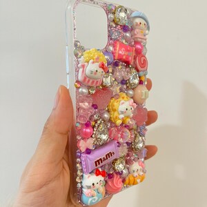 Pu&ograve; includere: Una custodia per telefono rosa e viola con glitter e una variet&agrave; di ciondoli colorati, tra cui personaggi dei cartoni animati, caramelle e strass.