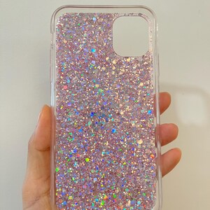 Pu&ograve; includere: Una custodia per telefono trasparente con un design di glitter rosa e iridescente.