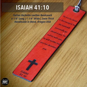 May include: Red Italian Vachetta leather bookmark with the text "ISAIAH 41:10" and a cross. The bookmark is 6 1/4 inches long, 1 1/4 inches wide, and 2mm thick. It features an inspirational quote.