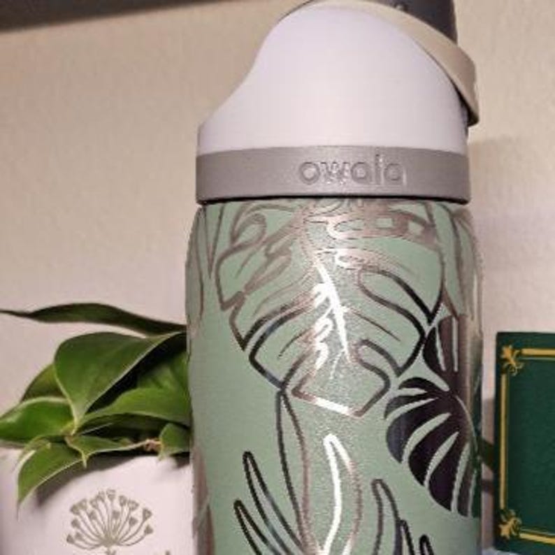 Może przedstawiać: Biały ceramiczny kubek z czarnym uchem i napisem "But First, Coffee" czarną, odręczną czcionką. Kubek ma prawdopodobnie pojemność 325-444 ml, idealny na poranny nap&oacute;j.