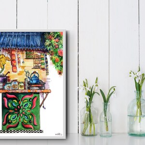May include: Watercolor painting of a vibrant tea stall with a blue roof and green and red accents. A blue teapot steams on a small stove. The stall is decorated with colorful patterns and surrounded by flowers. The painting is framed and displayed with vases of white flowers.