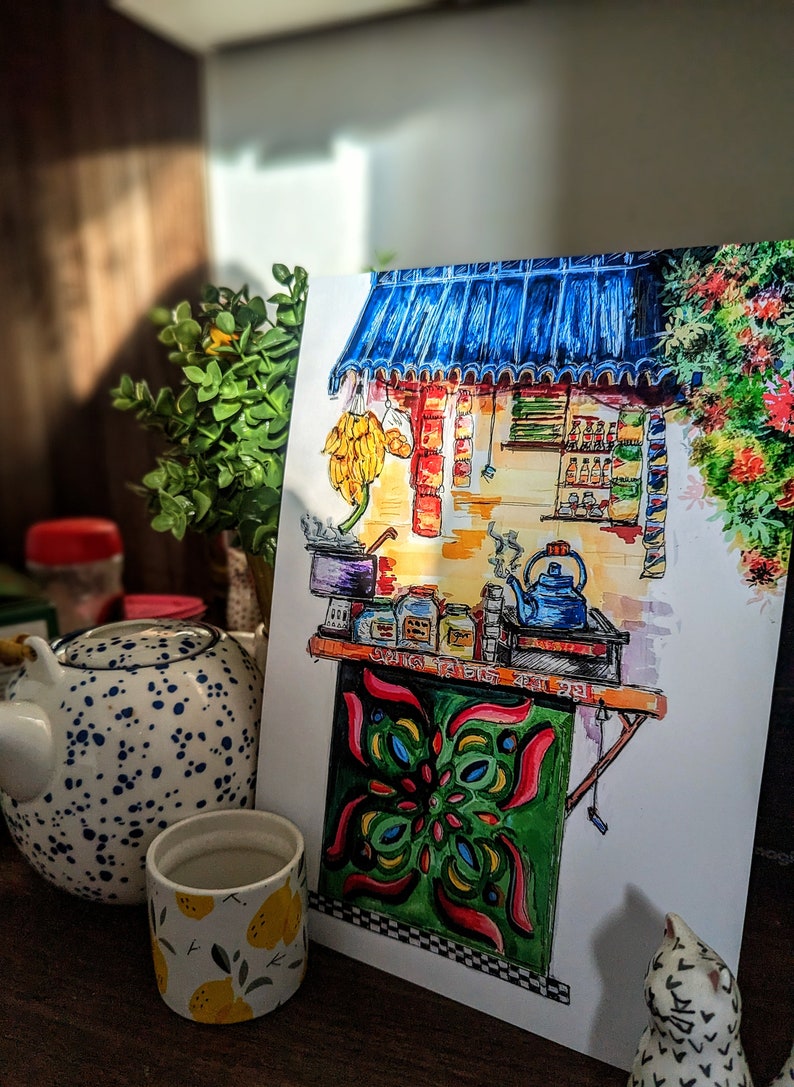 May include: Watercolor illustration of a tea stall with a blue awning, bananas, and various jars. The stall has a green and red patterned front. A blue teapot and a cup with lemons are in the foreground.