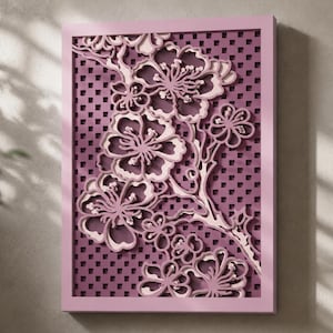 May include: A rectangular wall art piece featuring a layered, three-dimensional cutout design of cherry blossom branches. The artwork displays shades of light and dark purple, set against a grid-patterned background within a solid purple frame.