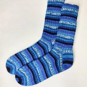 Pode incluir: Um par de meias listradas azuis e pretas com manchas brancas. As meias são feitas de um material macio e confortável e são perfeitas para o uso diário.