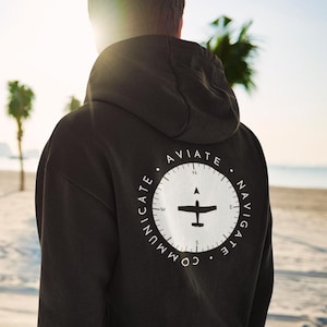 May include: Black hoodie with a white compass design on the back. The compass features a small airplane and the words "AVIATE", "NAVIGATE", "COMMUNICATE".