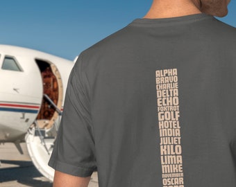 Könnte beinhalten: Ein dunkelgraues T-Shirt mit einer vertikalen Liste des NATO-Phonetischen Alphabets, das in hellbrauner Farbe auf der Rückseite aufgedruckt ist.