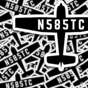 May include: Black and white sticker of a small aeroplane with the tail number N585TC printed on it. The sticker is surrounded by other stickers with the same design but different tail numbers.