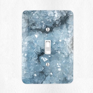 May include: A light switch cover with a blue and white crystal design.