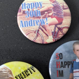 May include: Three round buttons with photos and text. The first button has a photo of a young boy on a bicycle with the text "Happy 30th Andrew!" The second button has a photo of a young boy with the text "Thirty & flirty". The third button has a photo of a young boy with the text "So Happy Im Thirty".