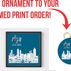 Op de afbeelding: Een gepersonaliseerde blauwe en witte ornament met een stadsbeeld en de tekst "John & Jeff 12.31.2024 Atlanta, Georgia".