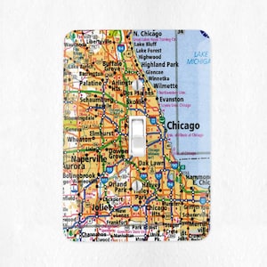 May include: A light switch cover featuring a map of Chicago and surrounding areas. The map is in a vintage style with colorful roads and city names. The switch cover is white with a black toggle switch.