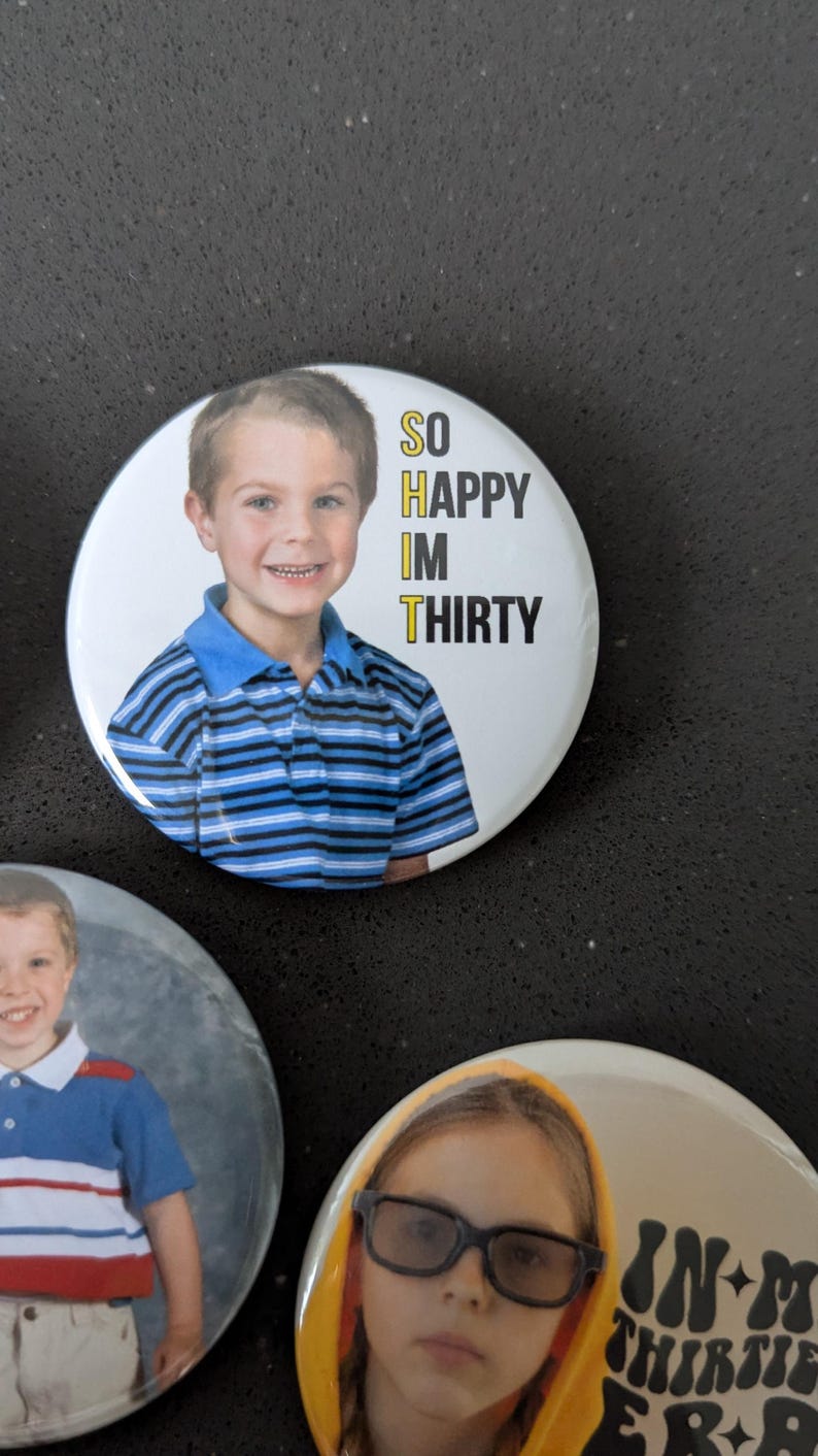 May include: Two round buttons with photos of children and text. The first button has a photo of a young boy wearing a blue and white striped shirt. The text reads "SO HAPPY IM THIRTY". The second button has a photo of a young girl wearing a yellow hoodie and glasses. The text reads "IN MY THIRTIES ERA".