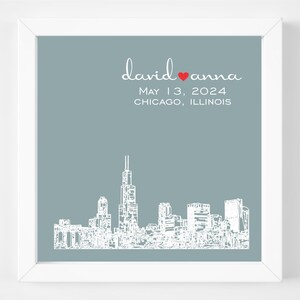 Op de afbeelding: Een lichtblauwe printbare huwelijksaankondiging met een witte omtrek van de skyline van Chicago en de tekst "david &hearts; anna" en "May 13, 2024 CHICAGO, ILLINOIS".