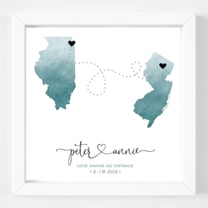 May include: A watercolor print of the states of Illinois and New Jersey with a dotted line connecting them. The text "peter & annie" is written in cursive with a heart symbol between the names. The text "LOVE KNOWS NO DISTANCE" and "12.18.2021" is written below the names.