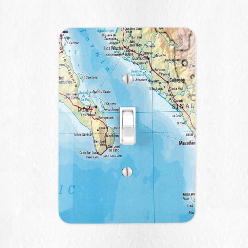 Pode incluir: Uma tampa de interruptor de luz com um mapa da pen&iacute;nsula da Baja California e da costa oeste do M&eacute;xico. O mapa &eacute; impresso em um fundo branco com &aacute;gua azul e terra verde. A tampa do interruptor &eacute; branca e tem um interruptor de luz no centro.
