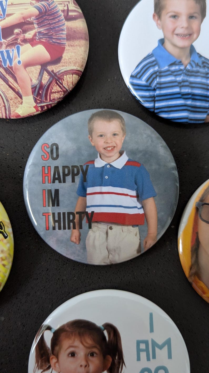 May include: Four round buttons with photos of children and text. The first button shows a child riding a bicycle. The second button shows a child wearing a blue and white striped shirt with the text "SO HAPPY I'M THIRTY". The third button shows a child wearing a blue and white striped shirt. The fourth button shows a child with pigtails wearing a blue and white shirt with the text "I AM SO".