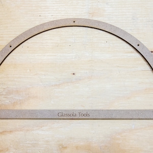 May include: A 10-inch wooden half-circle template with holes drilled along the curved edge. The template is labeled "Glassola Tools".