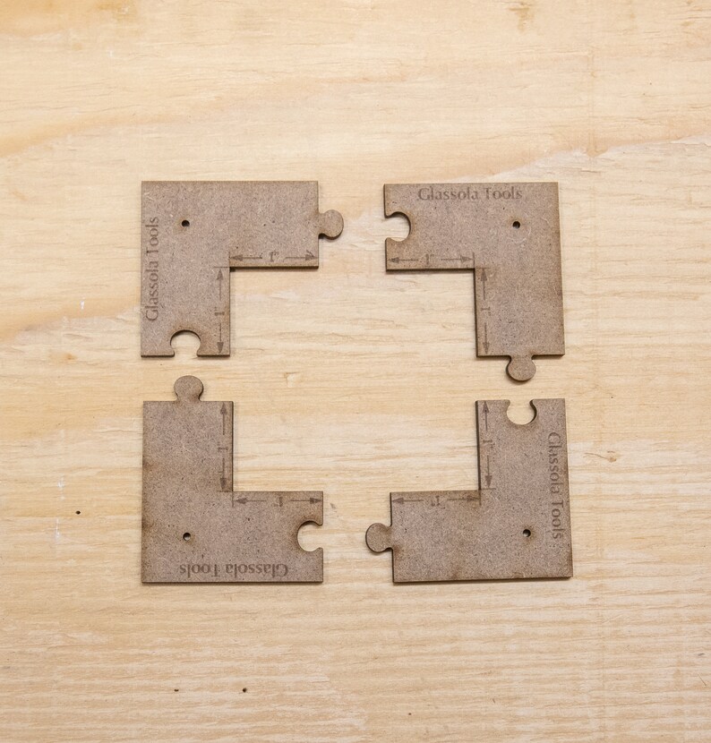 May include: Four brown wooden jigsaw pieces with the text "Glassola Tools" printed on each piece. The pieces are arranged in a square shape, with the text facing outwards.