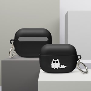 Könnte beinhalten: Zwei schwarze Silikonhüllen für kabellose Ohrhörer, eine mit einer weißen Comic-Katze mit Sonnenbrille, beide mit silbernen Schlüsselanhängern.