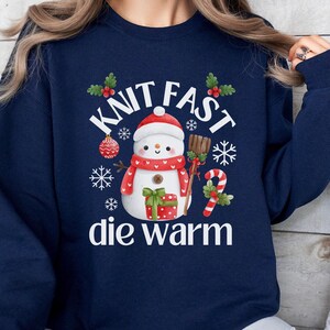 May include: Navy blue sweatshirt with a snowman graphic and the text "Knit Fast Die Warm".