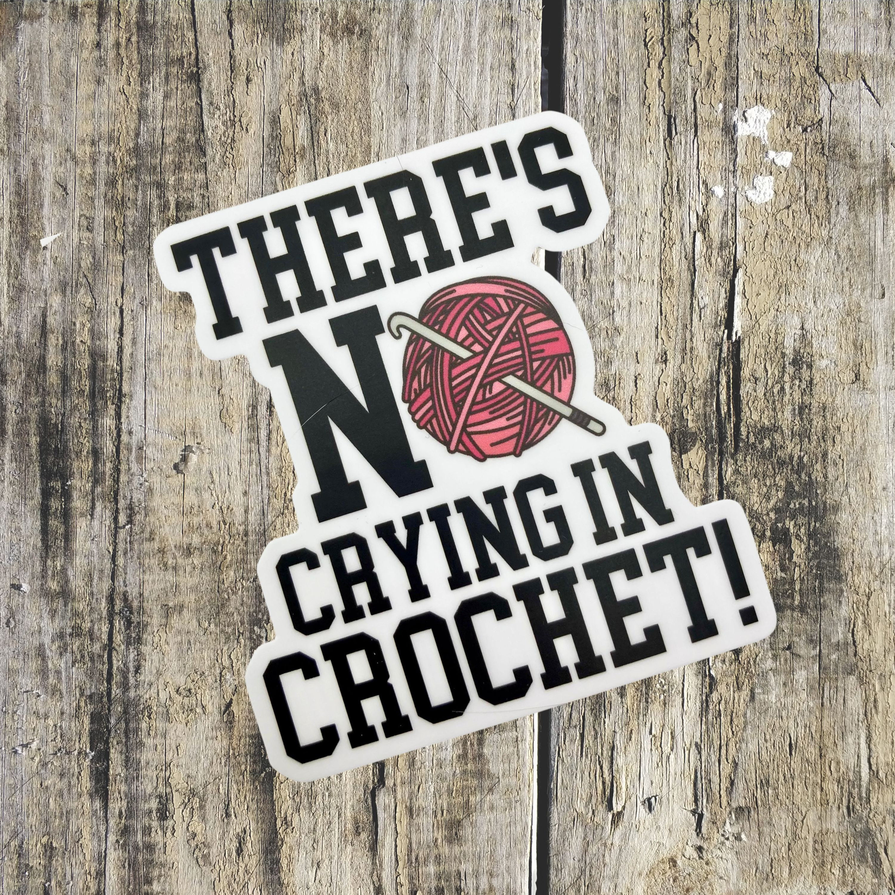 May include: White sticker with black text that reads "There's No Crying In Crochet!" with a pink yarn ball and crochet hook illustration.