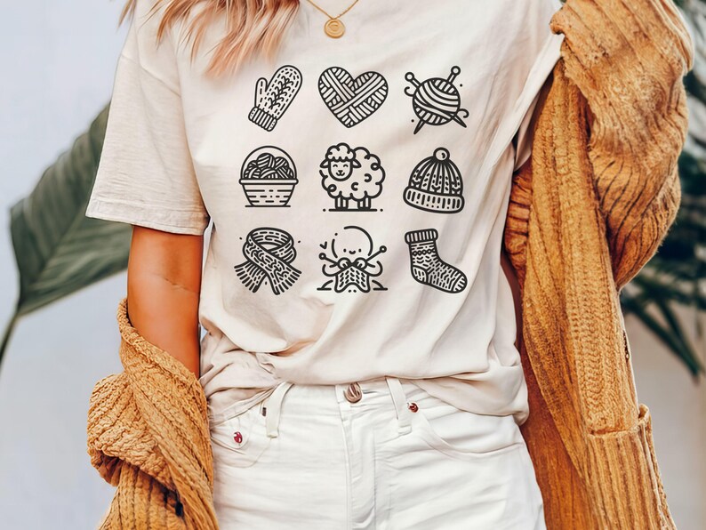 May include: A white t-shirt with a black and white graphic design of knitting-related icons. The icons include a heart, yarn ball, needles, a mitten, a basket of yarn, a sheep, a hat, a sock, and a hand knitting.