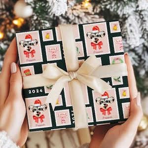 May include: A wrapped gift with a festive dog-themed wrapping paper. The paper features a repeating pattern of dog portraits wearing Santa hats and red bows, with the name "Pepper" below each image. The gift is tied with a gold ribbon and bow, with the year "2024" printed on the wrapping paper.