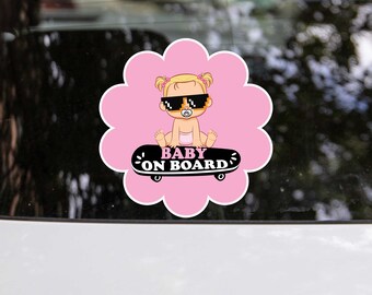 May include: Pink and black car sticker featuring a cartoon baby girl wearing sunglasses and a dummy, riding a skateboard. The text "BABY ON BOARD" is written on the skateboard.