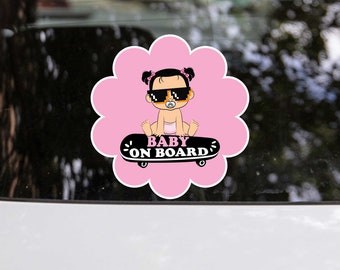 May include: Pink flower-shaped car sticker with a cartoon baby girl wearing sunglasses and a dummy, riding a skateboard. The sticker says "BABY ON BOARD".