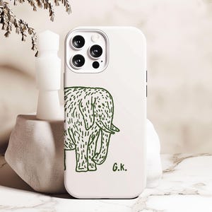May include: White phone case with a green line drawing of an elephant and the text "G.K." at the bottom.