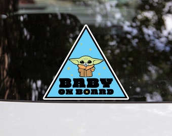 May include: A blue triangular car sticker featuring a cartoon character of a green alien with large ears and a dummy. The text "BABY ON BOARD" is printed in black lettering.