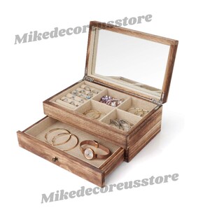 May include: A wooden jewelry box with a mirrored lid and a pull-out drawer. The box has compartments for rings, earrings, and other jewelry. The drawer is open and contains a watch.