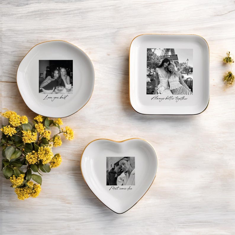 Peut inclure: Trois vide-poches en c&eacute;ramique blanche avec des bords dor&eacute;s, chacun avec une photographie en noir et blanc. L'un est rond, l'autre carr&eacute; et l'autre en forme de c&oelig;ur. Le plat rond dit "Love you best", le plat carr&eacute; dit "Always better together", et le plat en forme de c&oelig;ur dit "Meet me someday".