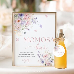 Könnte beinhalten: Ein druckbares Schild für eine Mimosa-Bar mit einem floralen Design und dem Text "MOMOSA bar" sowie Anweisungen zum "POUR THE BUBBLES, SPLASH IN SOME JUICE, ADD A FRUITY TWIST HERE, enjoy". Eine kleine Flasche Orangensaft mit einem floralen Etikett, auf dem "ORANGE juice" steht, befindet sich im Vordergrund.