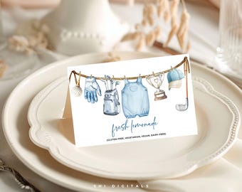 May include: Watercolor illustration of golf-themed items hanging on a clothesline, including a golf ball, glove, golf clubs, baby overalls, trophy, cap, and golf club. The card reads "fresh lemonade" and is on a white plate.