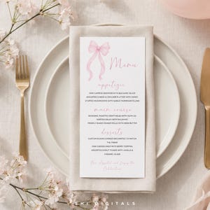 Op de afbeelding: Een menukaart met een roze strik ontwerp, geplaatst op een wit bord met een gouden vork en mes. Het menu bevat voorgerechten, hoofdgerecht en desserts. Roze kersenbloesems en een roze ballon op de achtergrond.