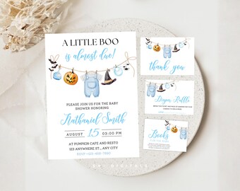 May include: A baby shower invitation set featuring a Halloween theme with a clothesline graphic displaying a blue baby romper, a witch hat, a pumpkin, and bats. The text reads A LITTLE BOO is almost due, Nathaniel Smith, August 15, 03:00 PM, and location details.
