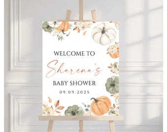 May include: A baby shower sign on an easel. The sign features watercolor pumpkins, flowers, and the text "Welcome to Sharena's Baby Shower" with the date 09.09.2025. The sign is decorated with orange, white, and green pumpkins.
