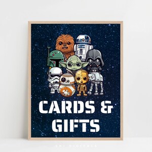 Pode incluir: Uma impressão emoldurada com versões de desenho animado de personagens de Star Wars, incluindo Chewbacca, Yoda e Darth Vader, contra um fundo azul estrelado. As palavras "CARDS & GIFTS" são exibidas em letras brancas em negrito.