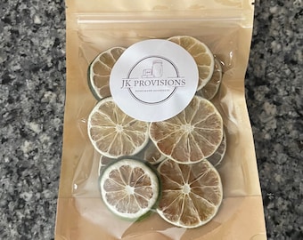 Pode incluir: Um saco de plástico transparente cheio de fatias de limão seco. O saco é selado e tem um exterior de papel castanho com um rótulo branco que diz "JK Provisions Homemade Goodness".