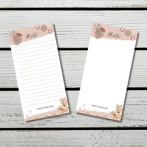 Peut inclure: Deux blocs-notes vierges avec un motif floral et le mot "Note" en haut. Les blocs-notes sont sur un fond en bois blanc. Le bas des blocs-notes porte le nom "Rose Schilling".